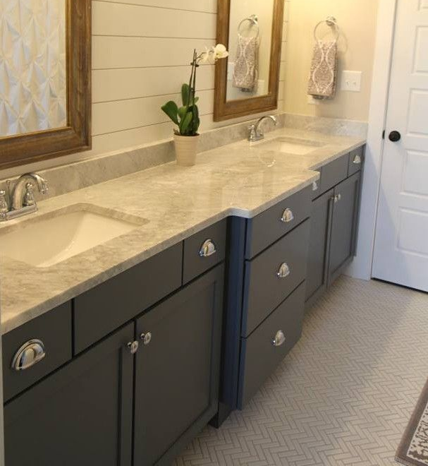Modern bathroom vanity with double sinks, dark cabinets, beige countertop, mirrors, and a white door