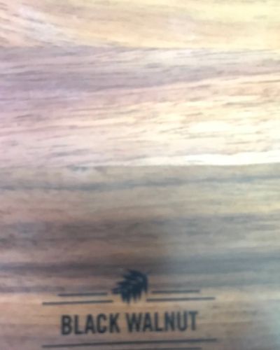 Close-up of a light wood surface labeled “BLACK WALNUT” with a small tree logo.