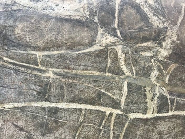 Close-up of gray stone wall with pale veining and cracks