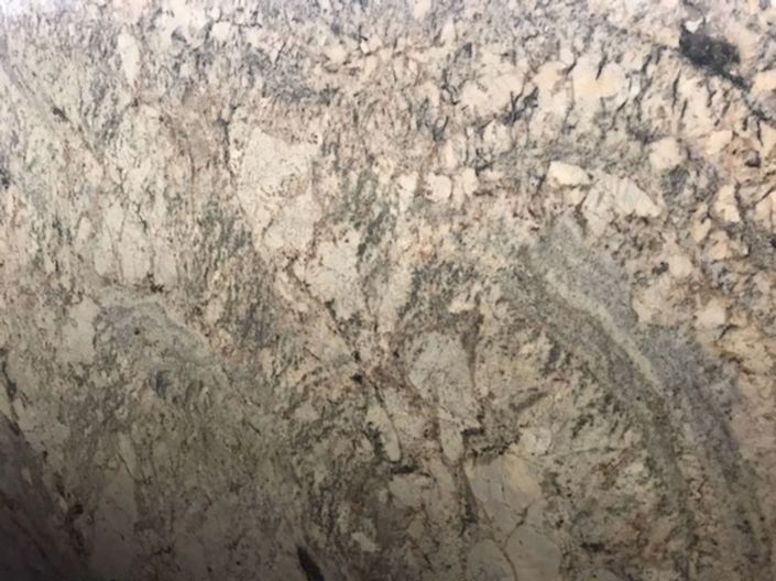 Close-up of a beige and gray marbled rock surface with dark veining and textured cracks