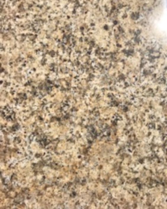 Close-up of a speckled beige granite countertop with black and brown flecks.