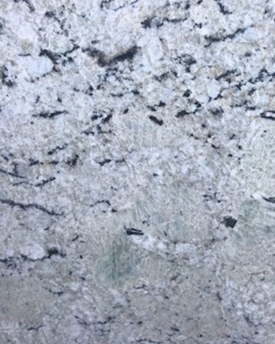 Close-up of a pale gray, speckled granite surface with dark flecks
