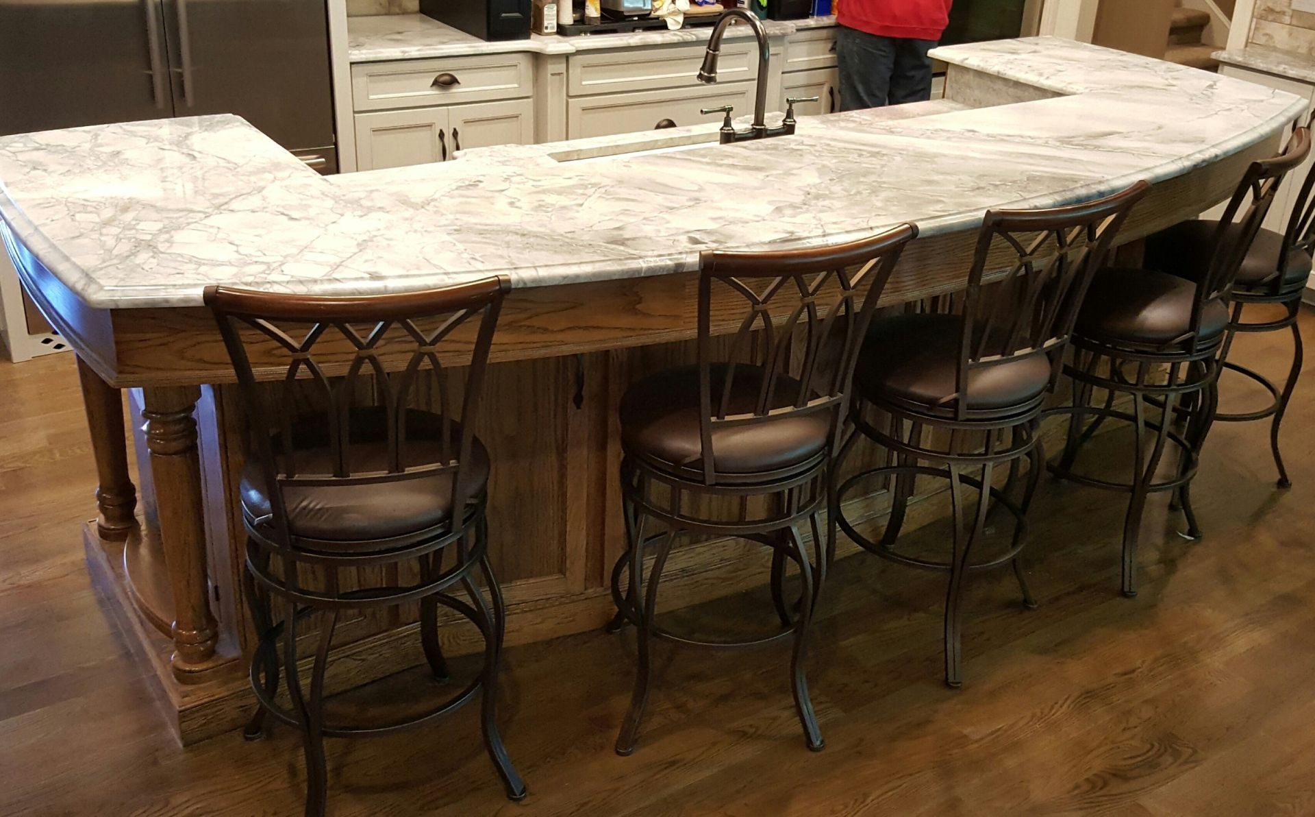 Curved stone kitchen island with ornate bar stools in a rustic interior