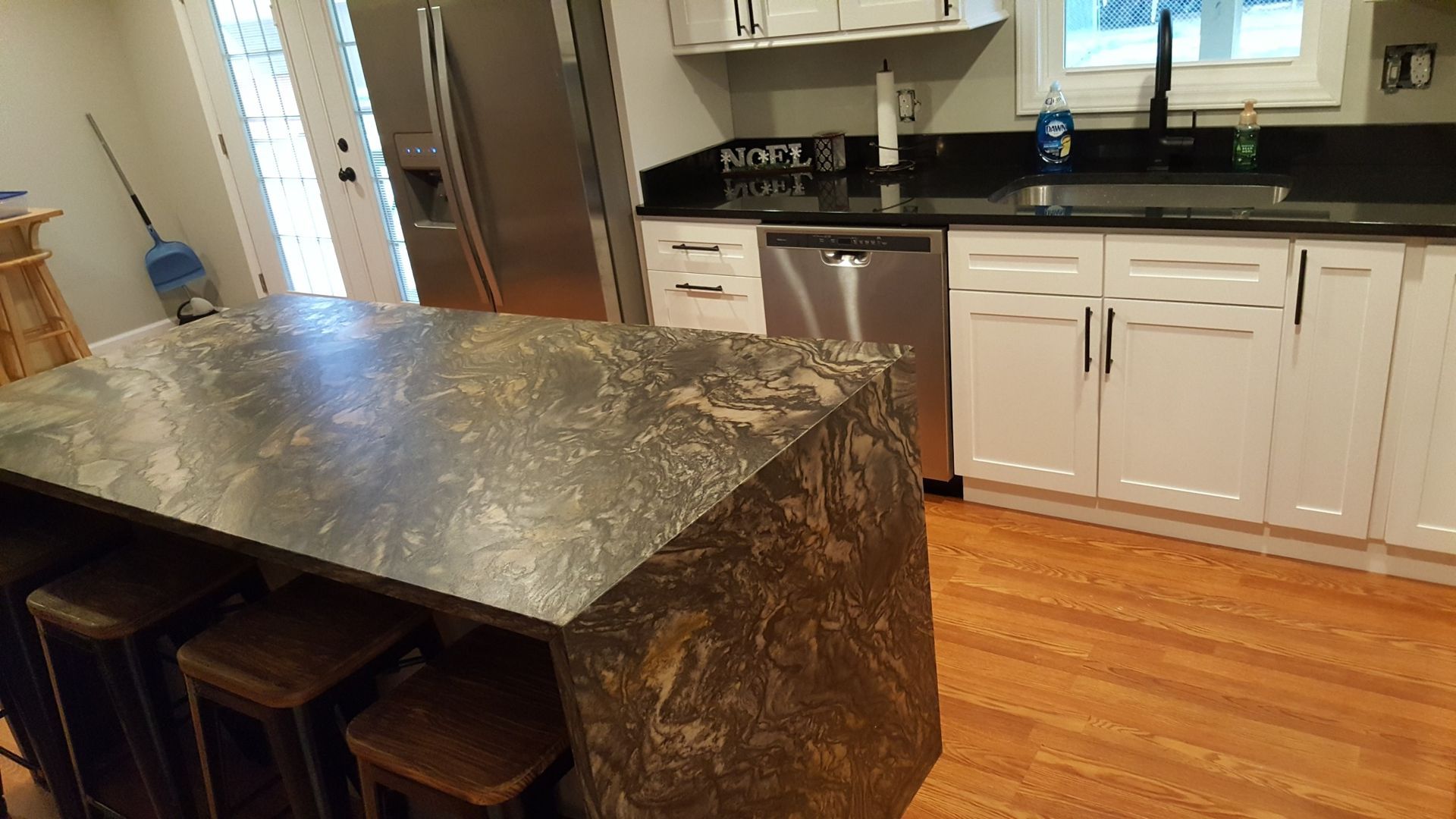 Modern kitchen with granite island, white cabinets, black countertops, and hardwood floors