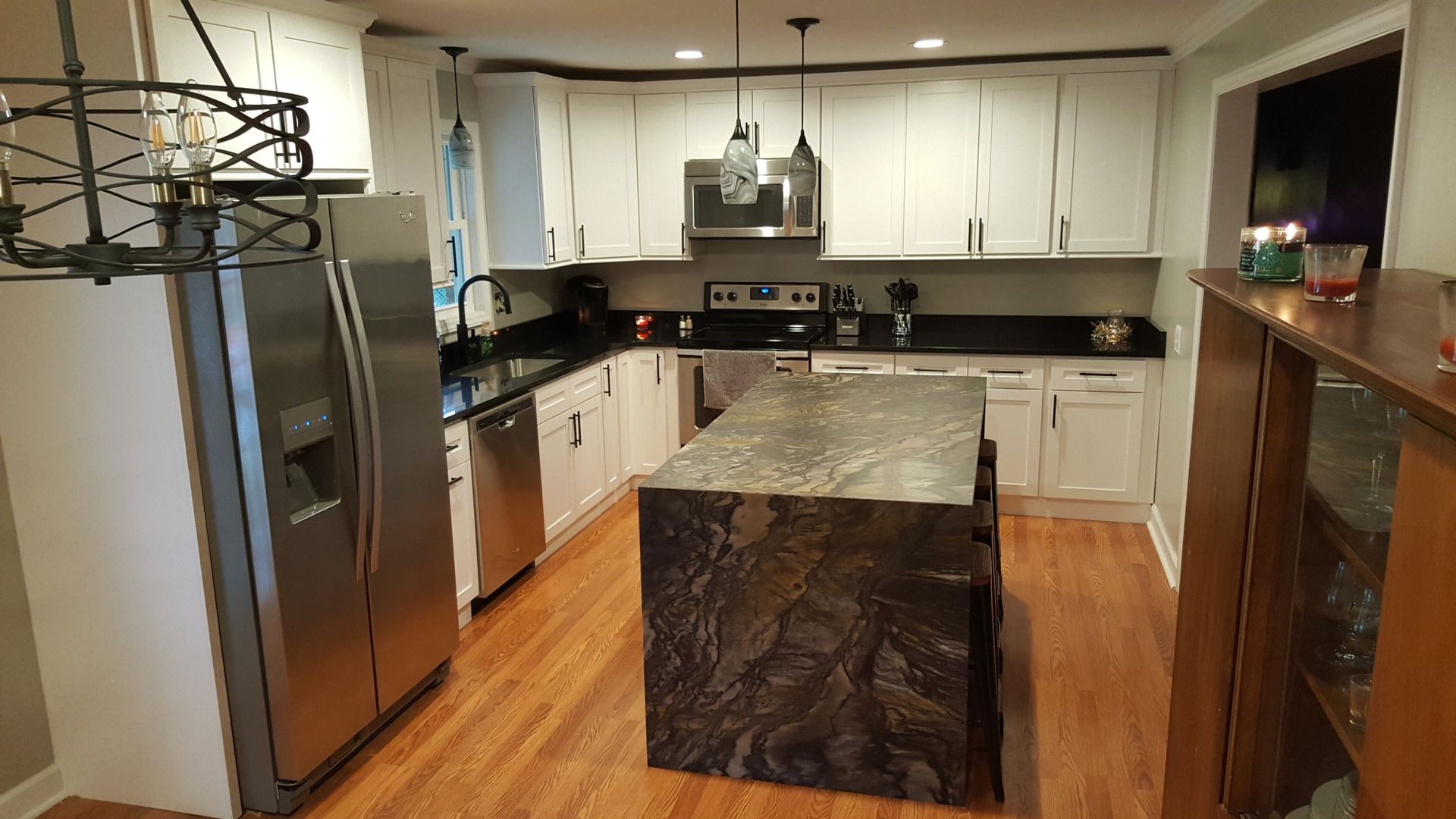 Modern kitchen with white cabinets, black countertops, a granite island, and stainless steel appliances