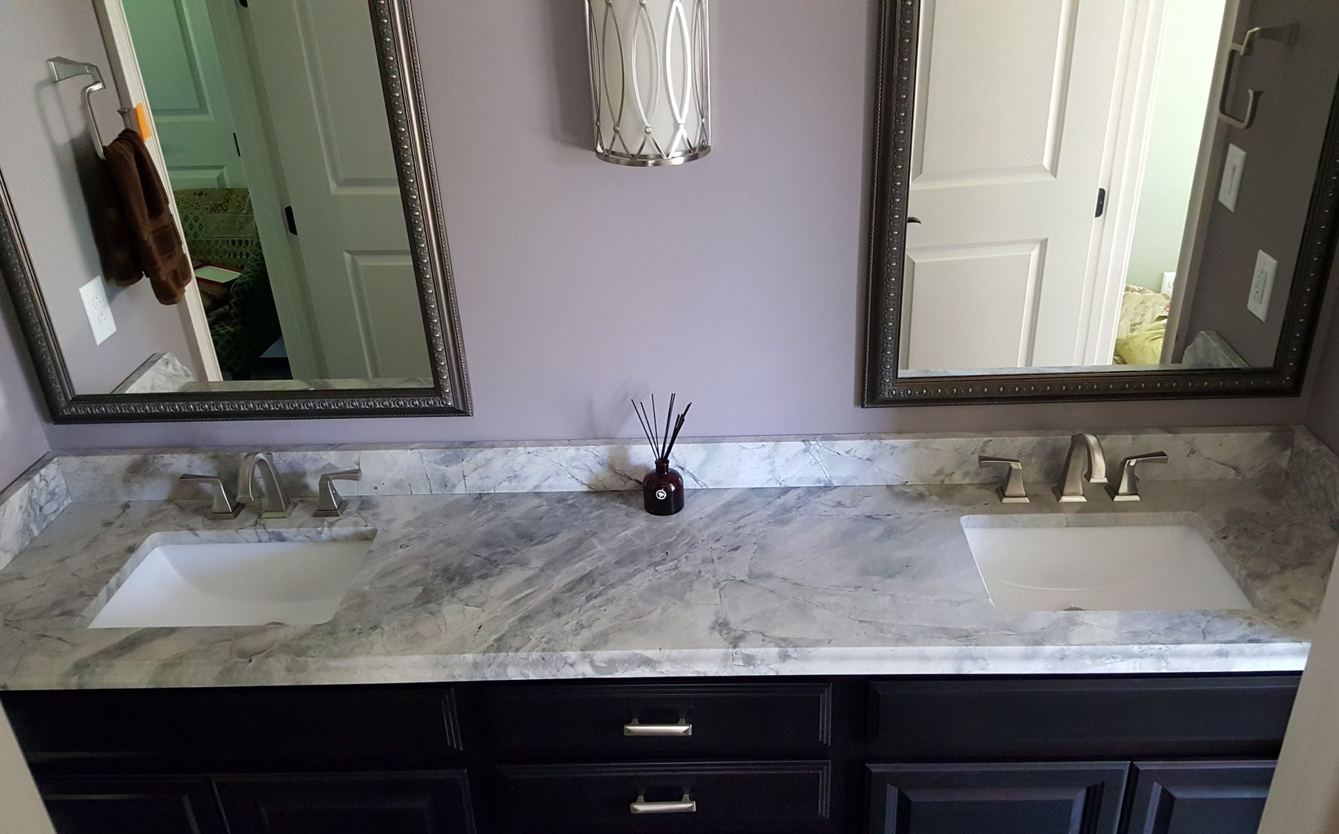 Double vanity bathroom with marble countertop, two mirrors, and dark wood cabinets