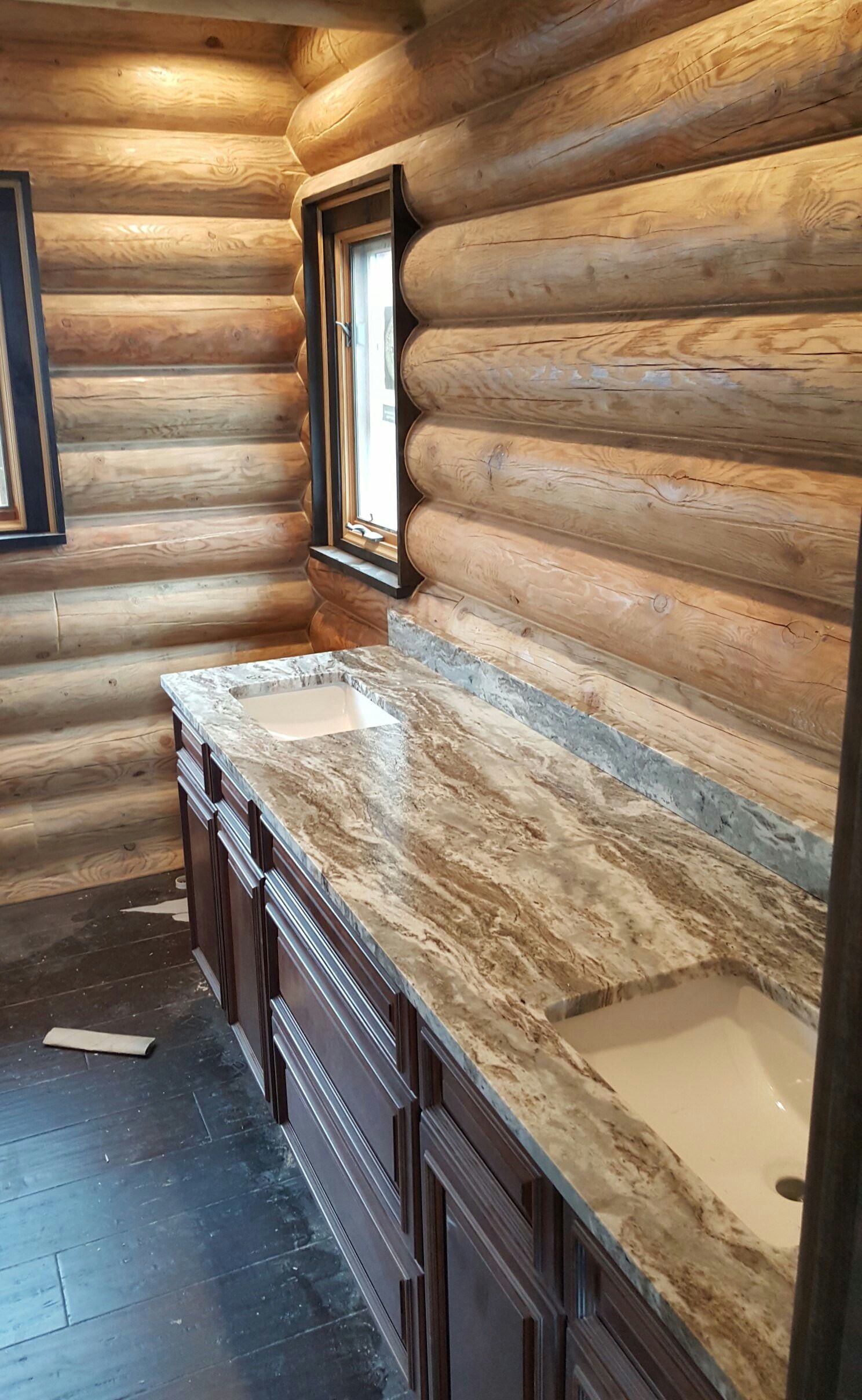 Log-cabin bathroom with granite countertop, wood walls, and a narrow window.
