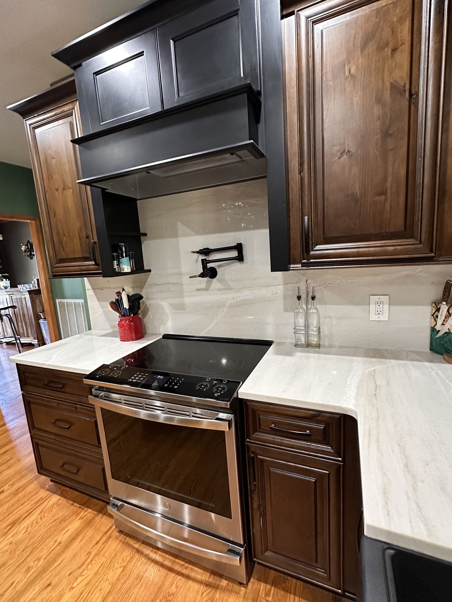 Modern kitchen with dark wood cabinets, stainless steel stove, and light countertops.