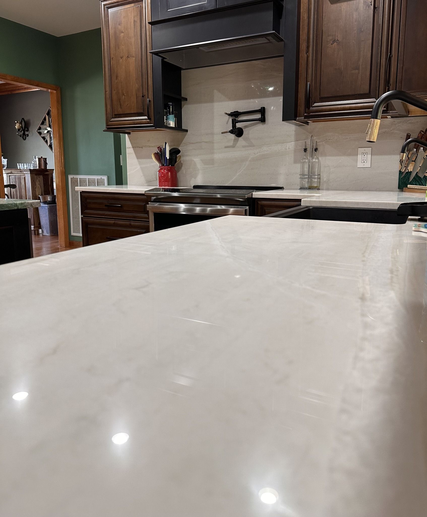 Kitchen with white countertop, wood cabinets, stainless stove, and beige tiled backsplash
