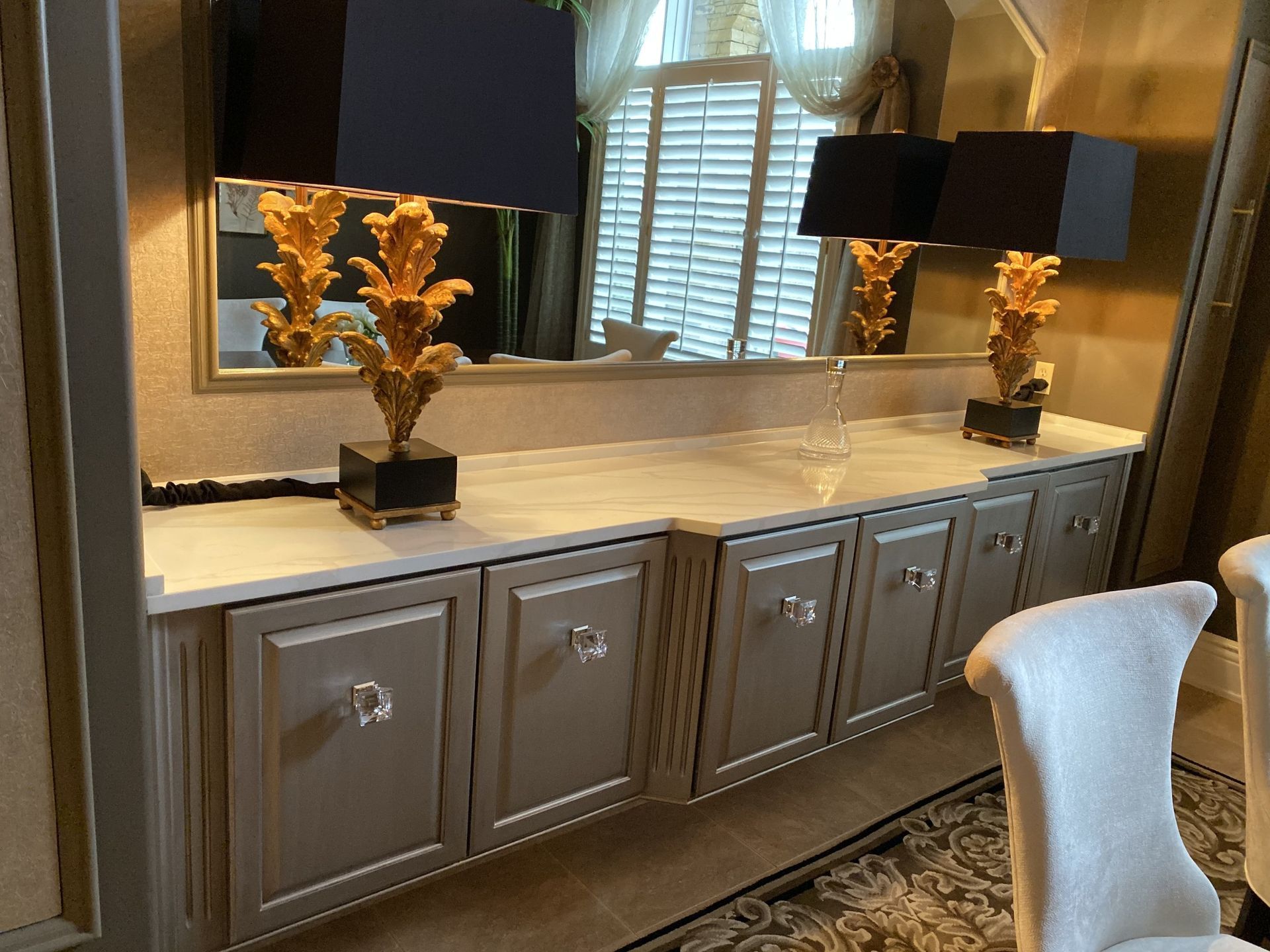Modern vanity with gray cabinets, large mirror, black lamps, and white countertop in a bathroom.