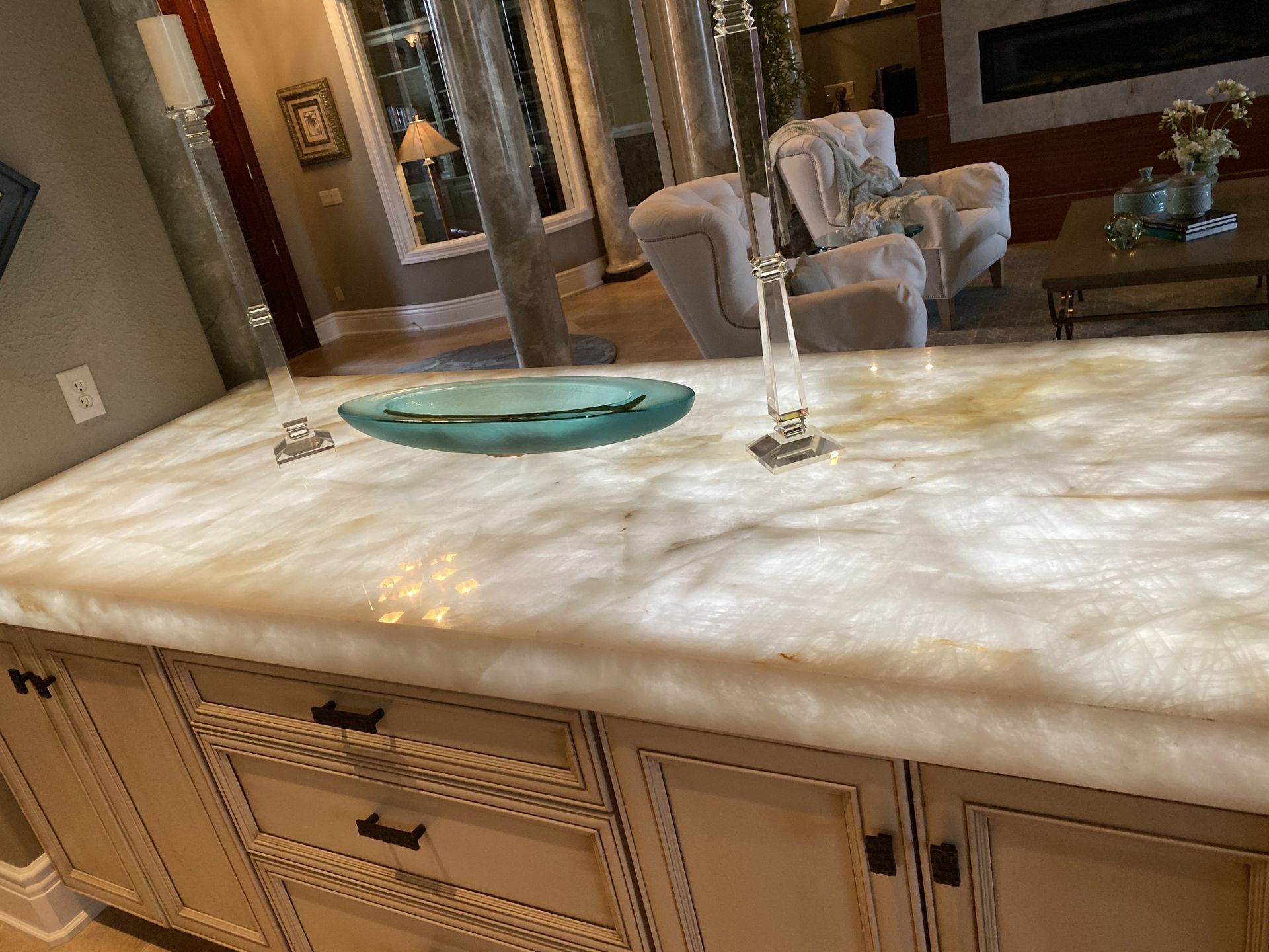 Kitchen island with marble countertop, teal tray, and decorative candlestick in a bright living room.