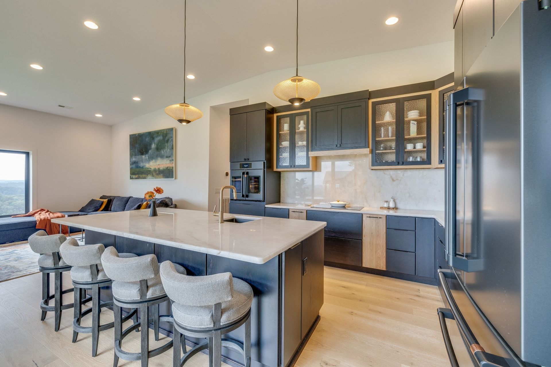 Modern kitchen with island, bar stools, gray cabinets, stainless appliances, and pendant lights