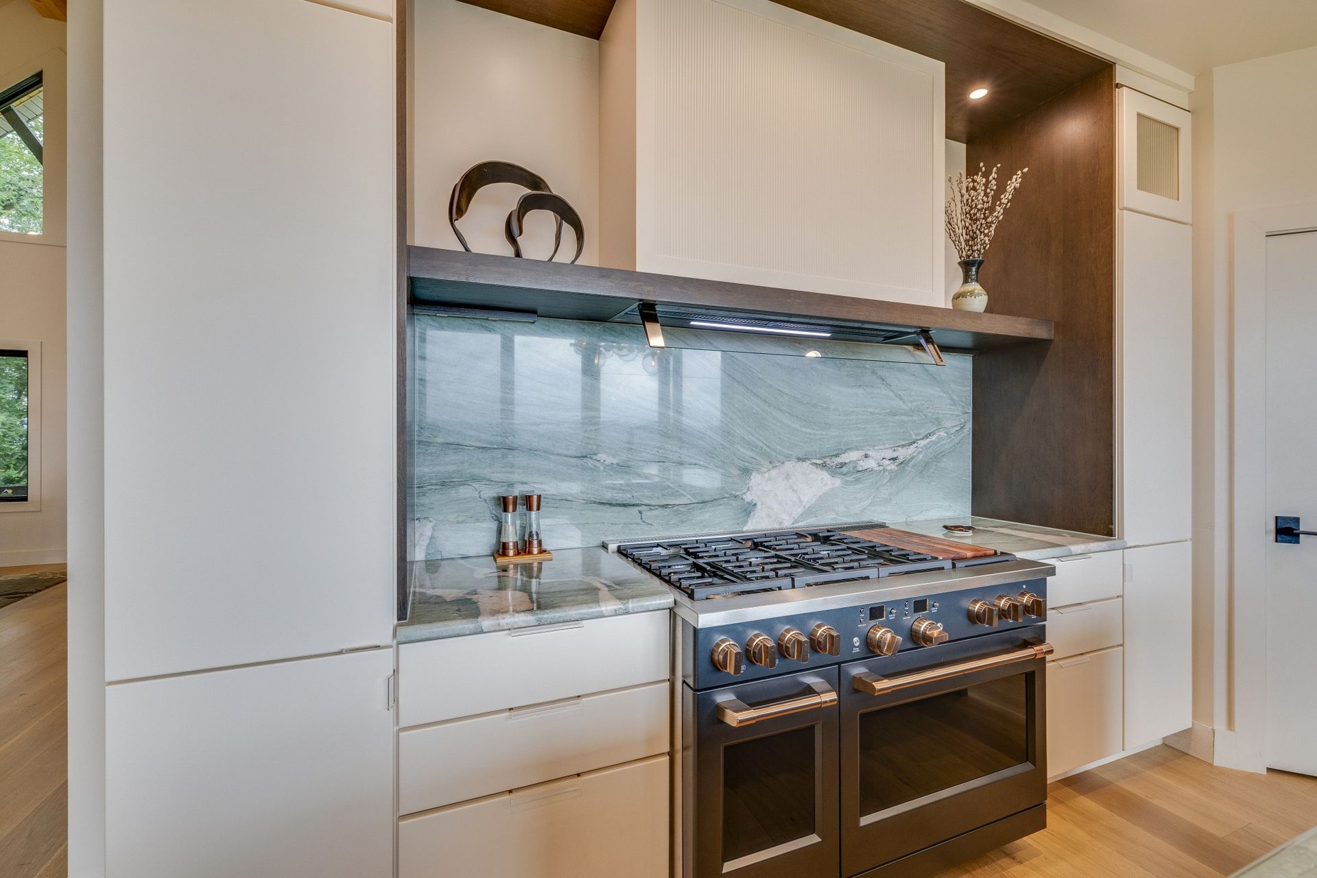 Modern white kitchen with marble backsplash and stainless steel gas range