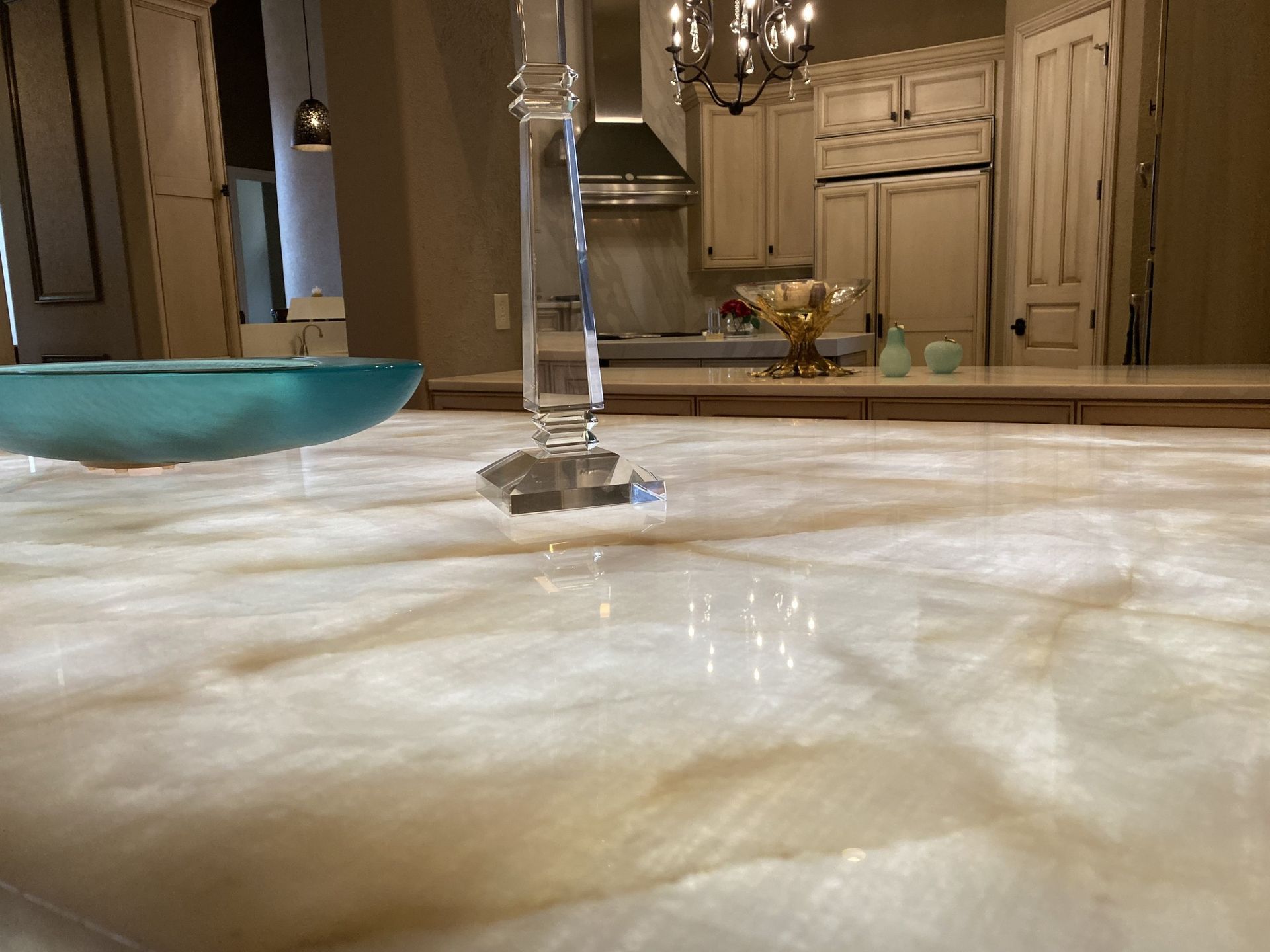 Water overflowing from a bathroom sink onto the countertop, with a blue bowl nearby and cabinets in the background