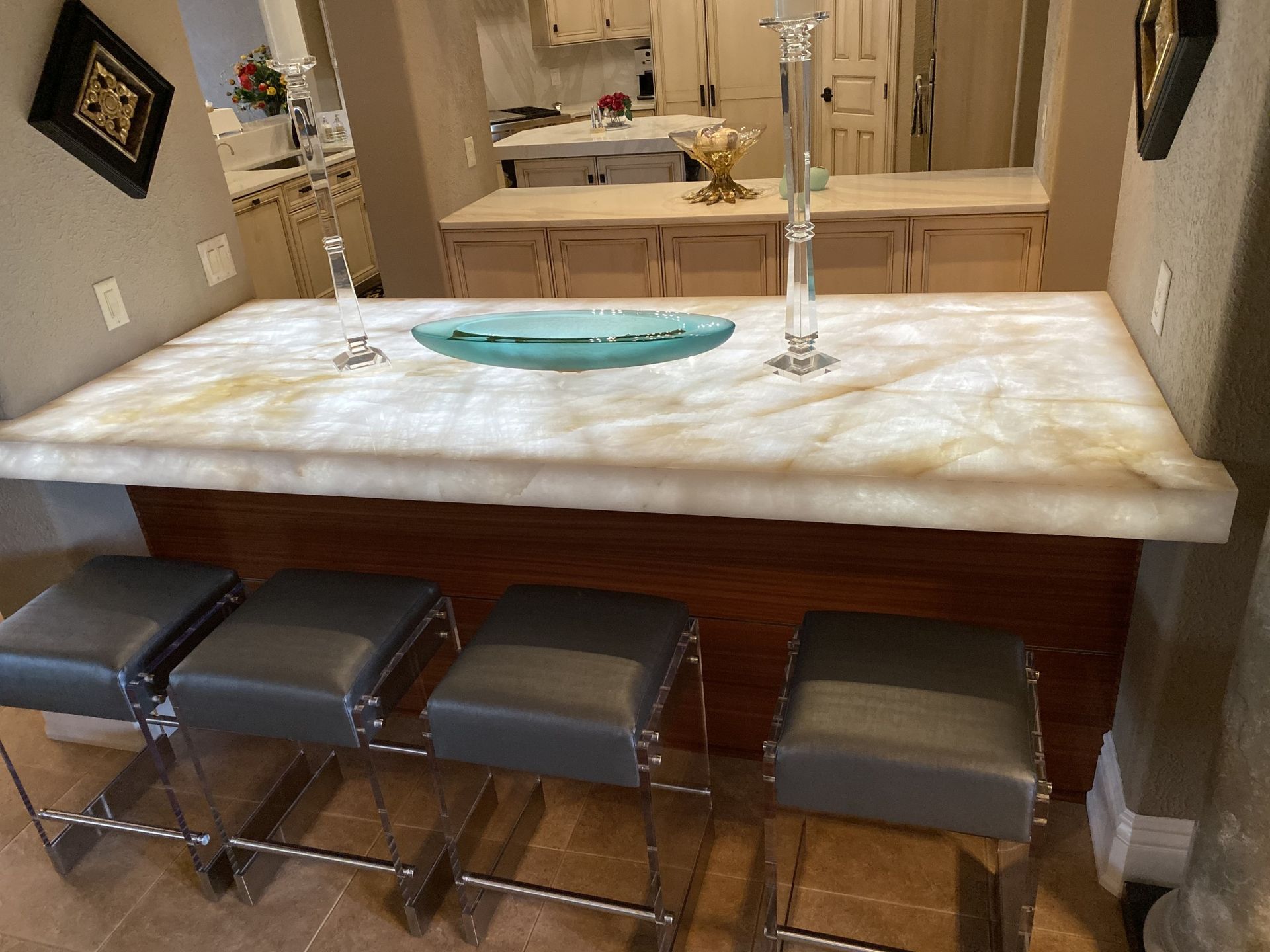 Modern bathroom vanity with marble countertop, vessel sink, and four stools beneath a large mirror.