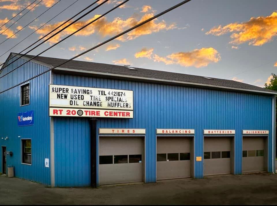 Blue RT 20 Tire Center building with garage doors, under a sunset sky.