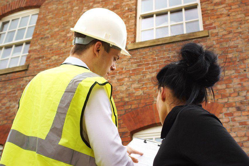A builder, contractor or surveyor pointing out an issue with a property to a homeowner
