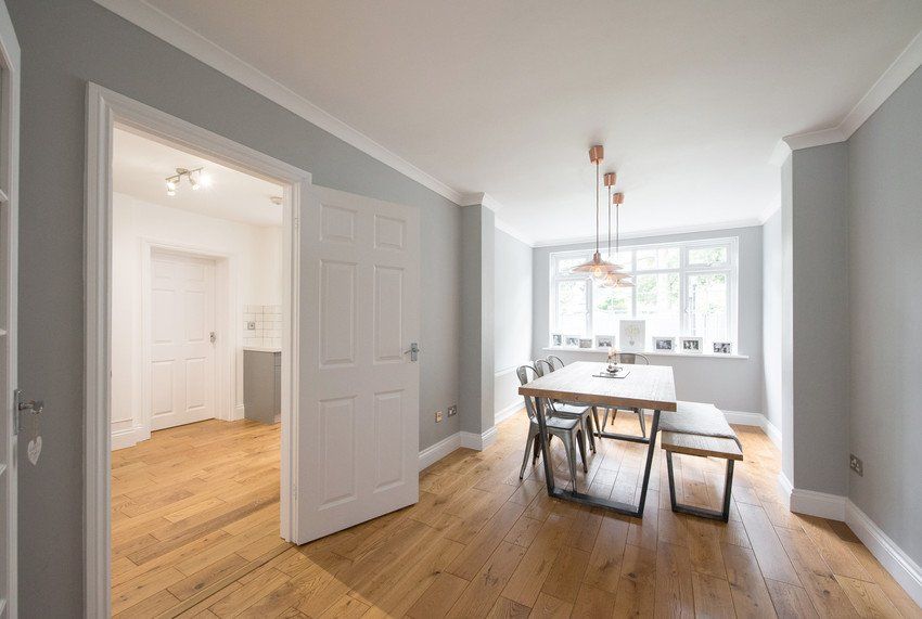 A general view of a dining room with grey walls and industrial style dining table with metal chairs and copper ceiling lights within a home