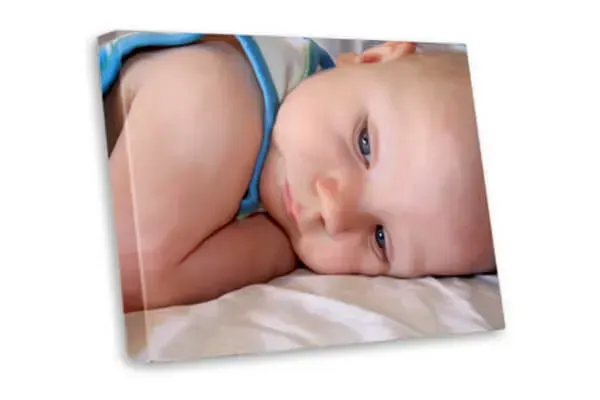 A baby is laying on a bed and looking at the camera.