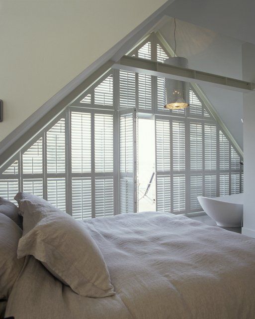 Grey bed with triangular shutter section in background