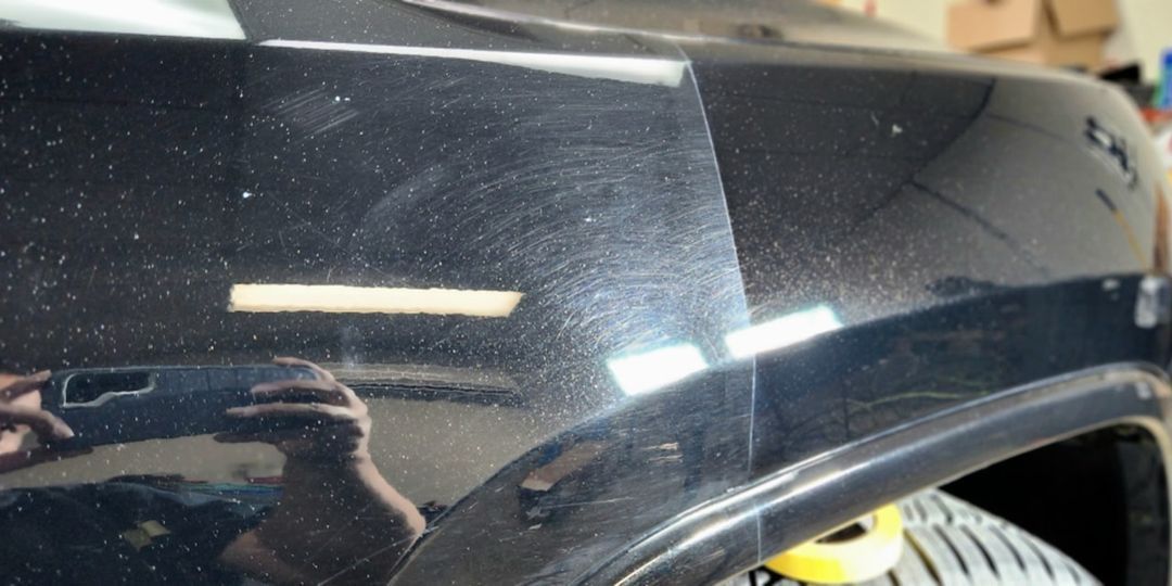A person is taking a picture of a black car.