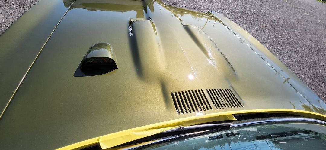 A close up of the hood of a yellow car.