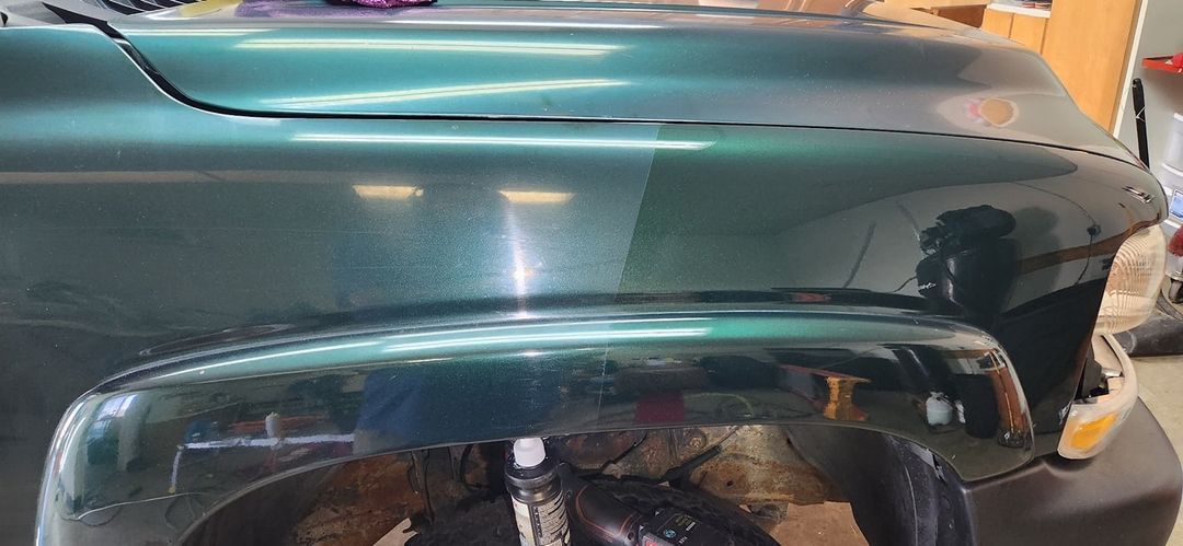 A green truck is sitting in a garage.