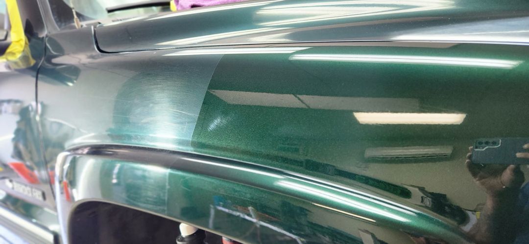 A green truck is parked in a garage.