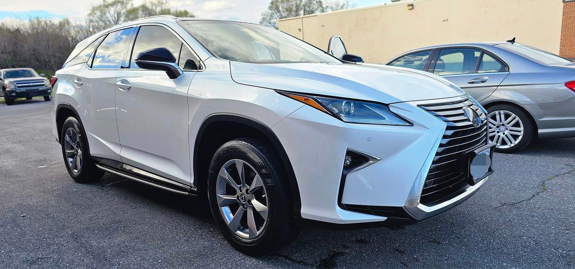 A white lexus rx is parked in a parking lot next to a silver car.
