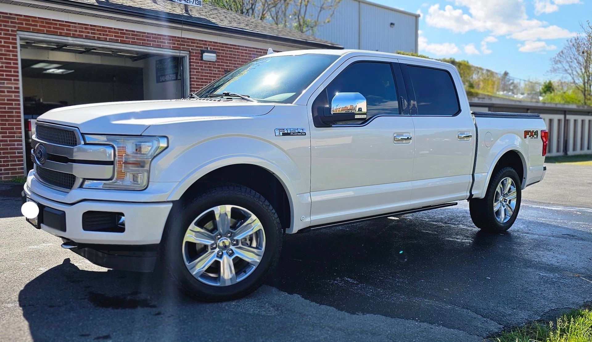 A white pickup truck is parked in front of a garage.