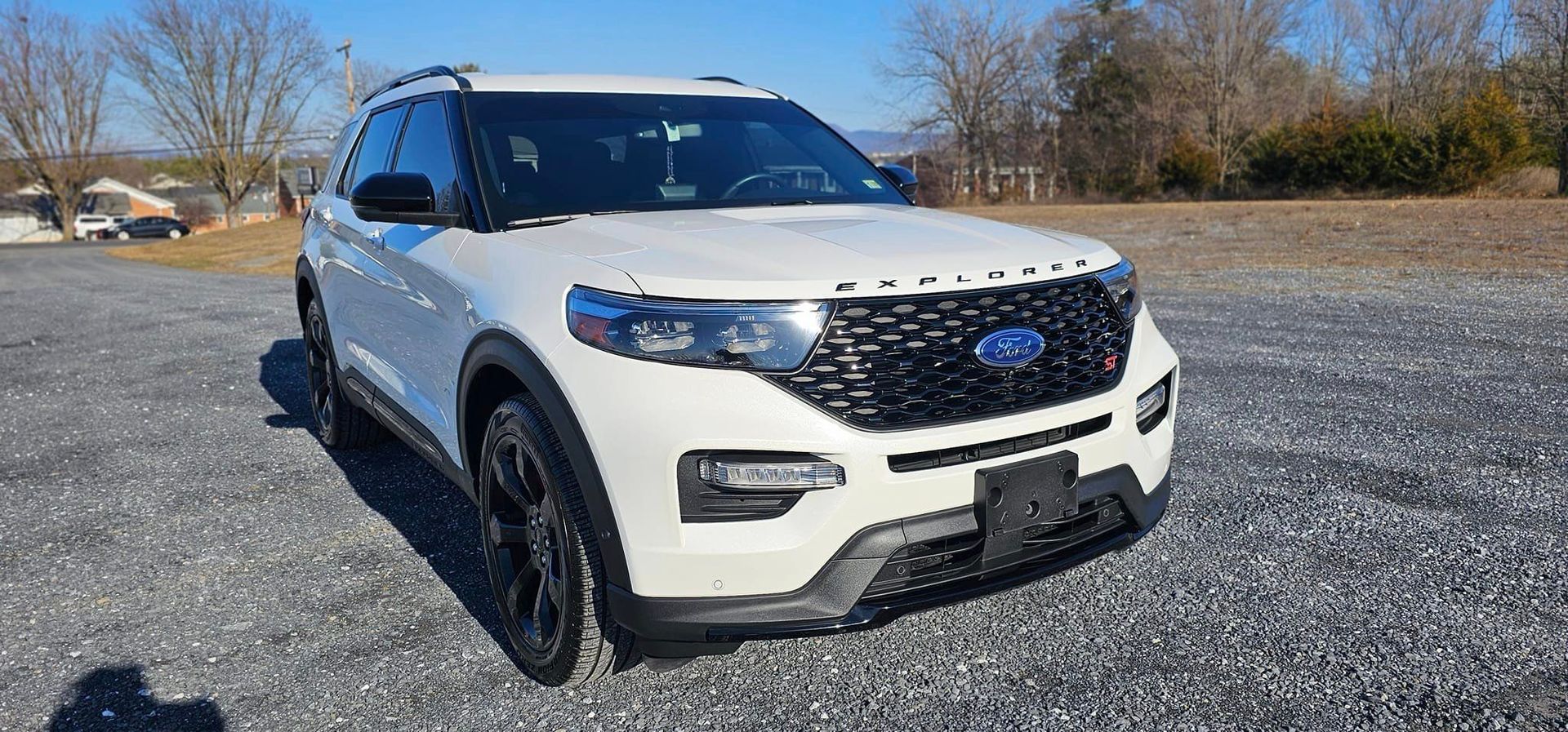 A white ford explorer is parked in a gravel lot.