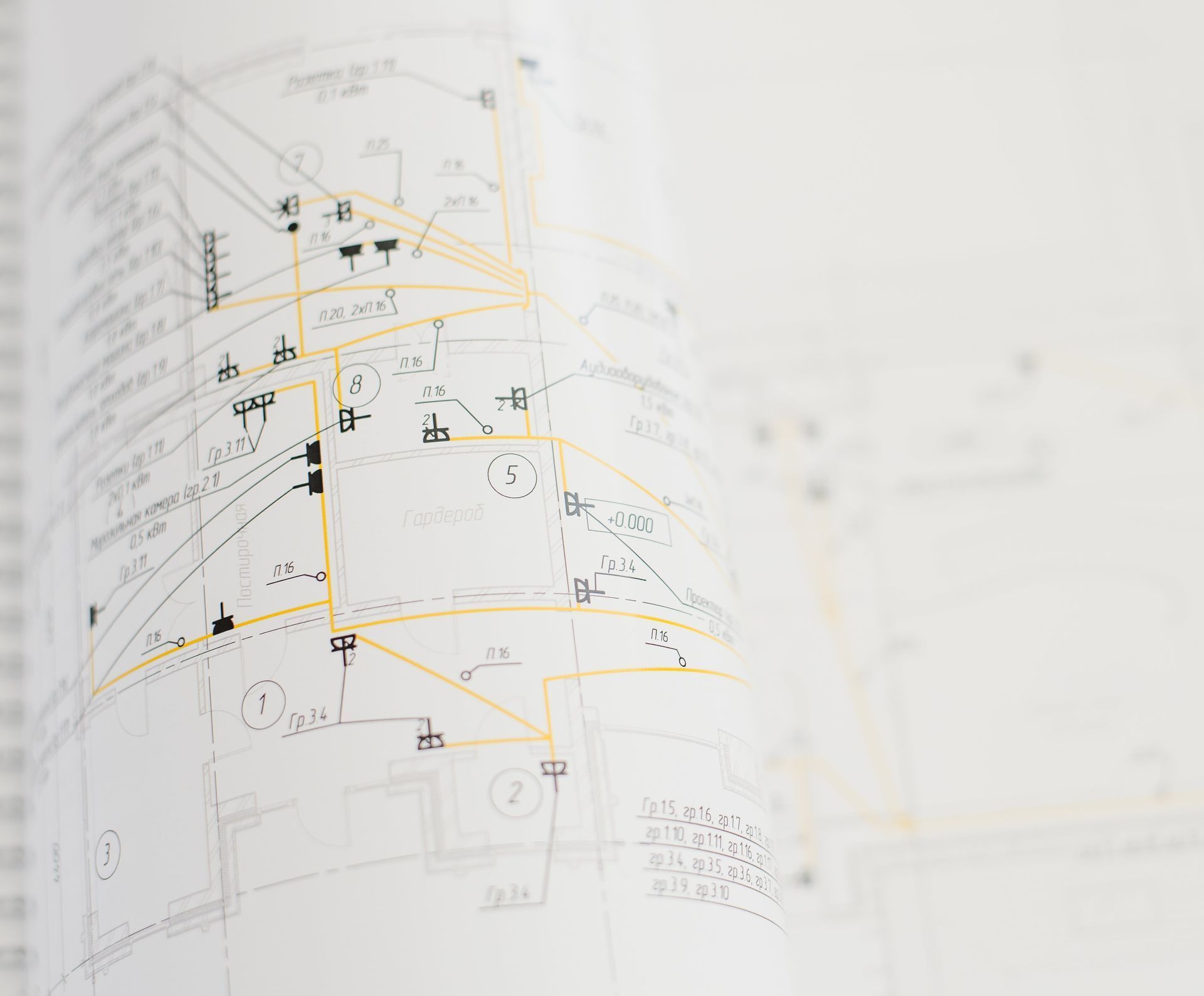 Architectural blueprint, partially rolled, with black and yellow lines, symbols, and text on white paper.