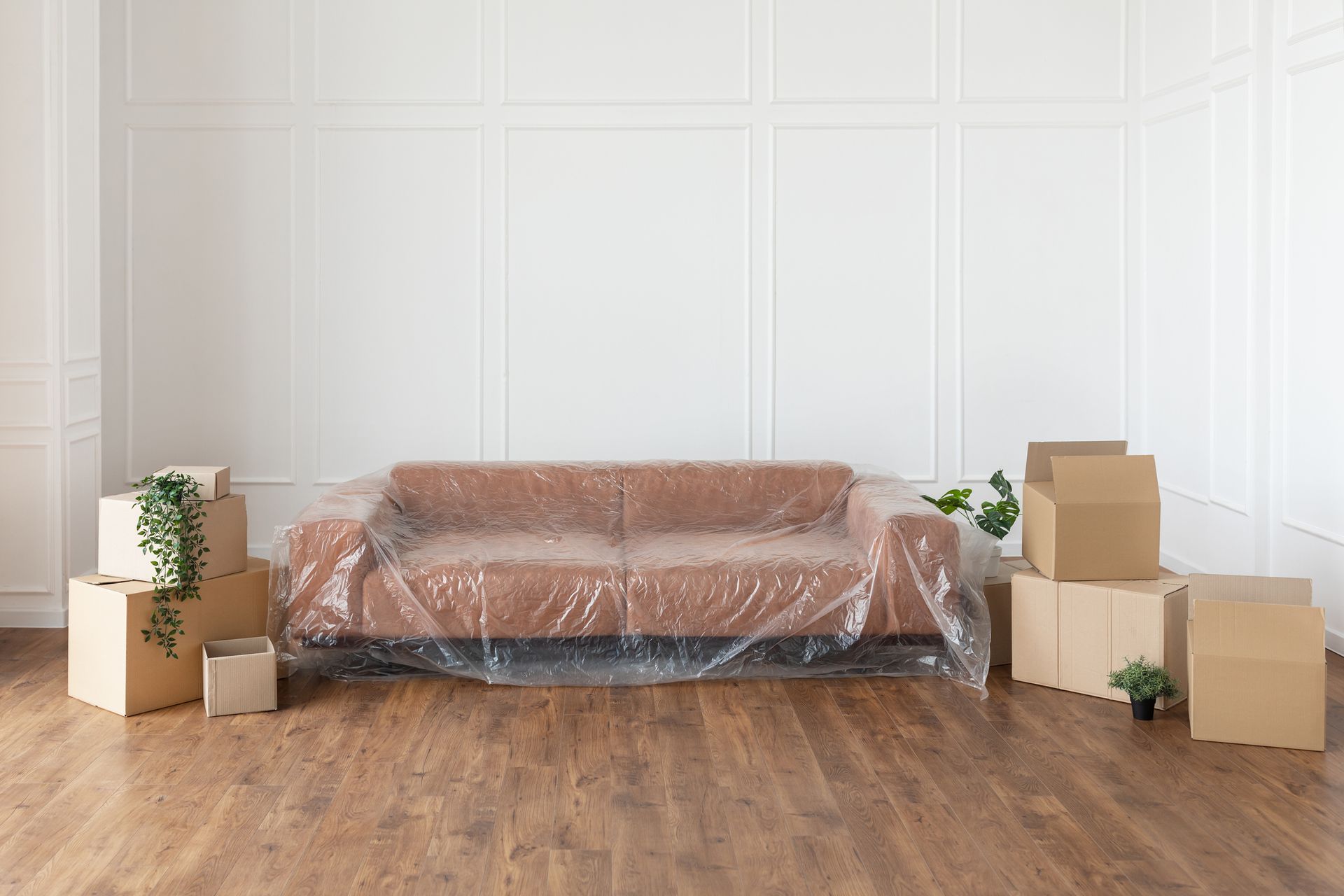 A brown couch is wrapped in plastic and surrounded by cardboard boxes – Springfield, OR - 42nd St Mini Storage