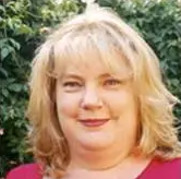 A woman with blonde hair and a red shirt is smiling for the camera.
