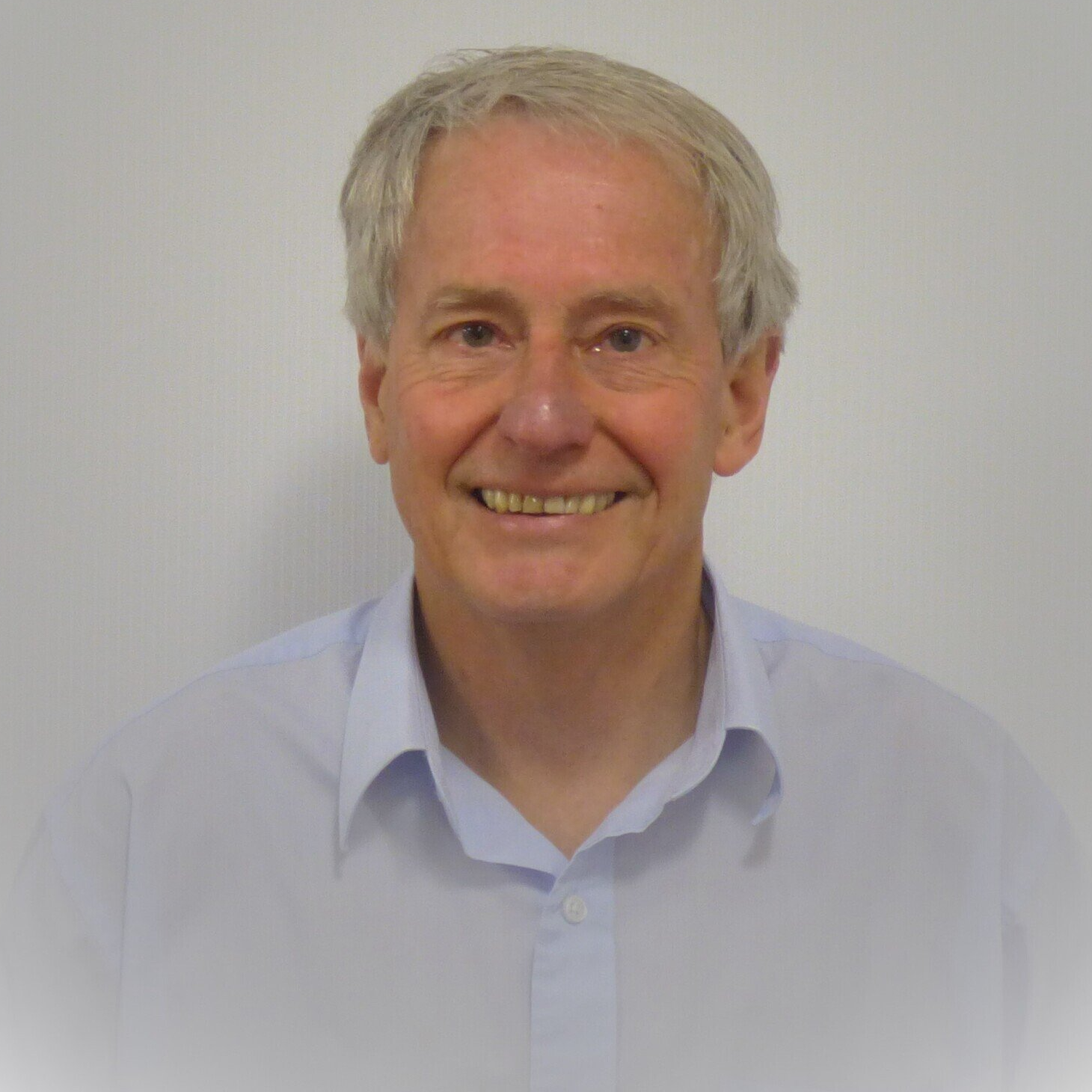 A man in a blue shirt is smiling for the camera