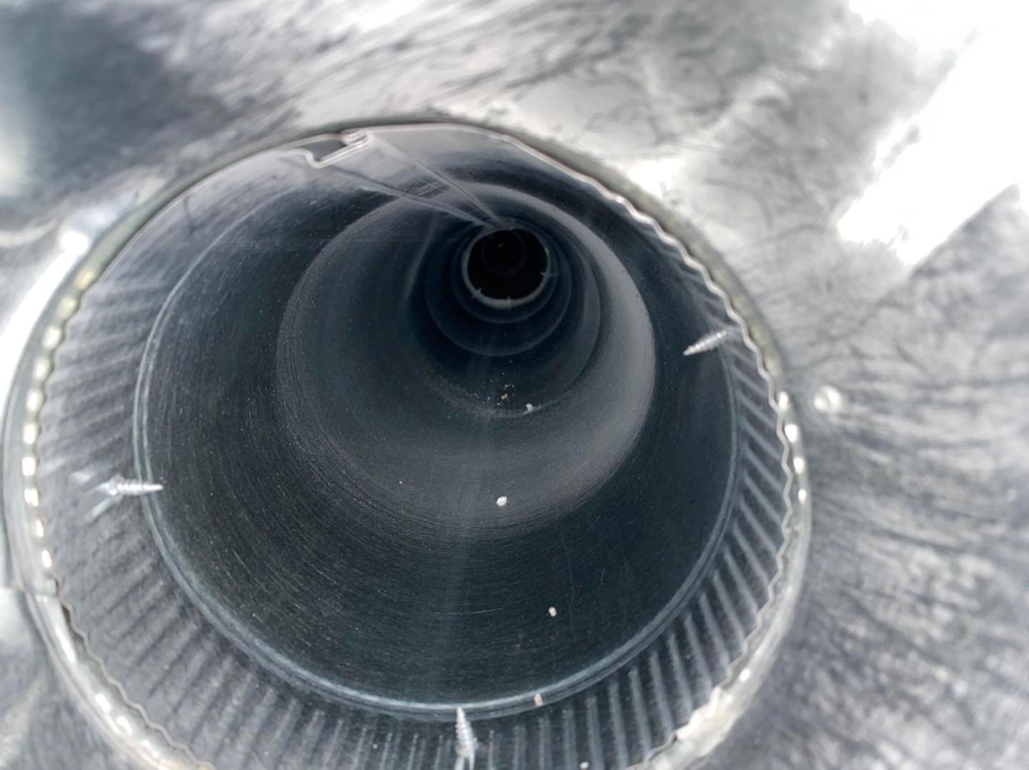 Close-up of a metallic cylindrical pipe or tunnel with a dark circular opening