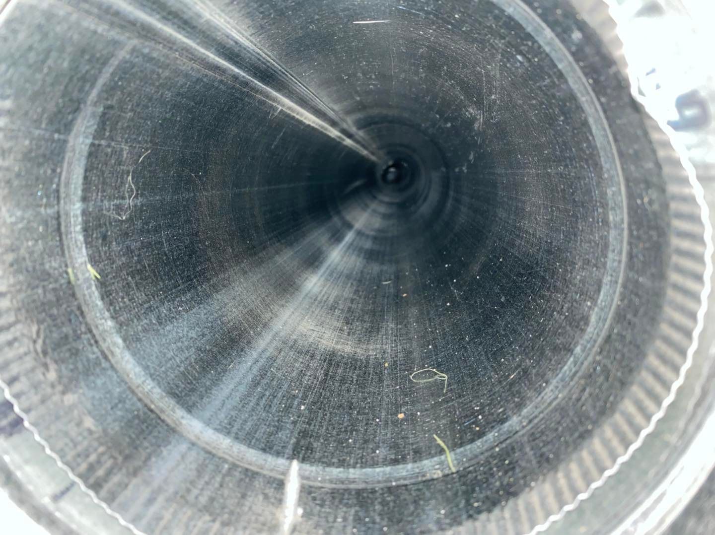Inside a metal pipe, looking down a dark, circular tunnel with reflective walls