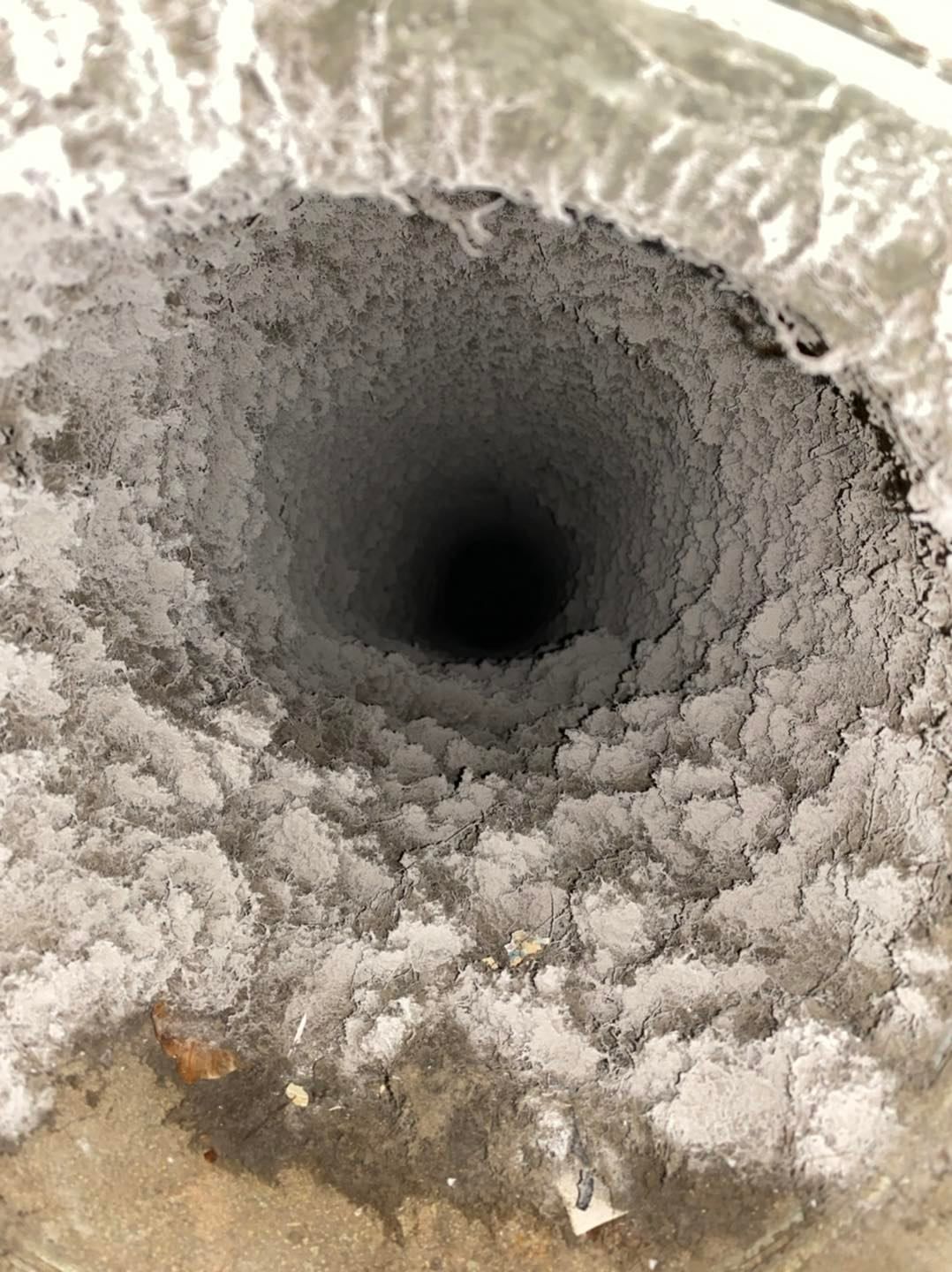 Close-up of a frosty circular pipe opening with icy white buildup around the rim