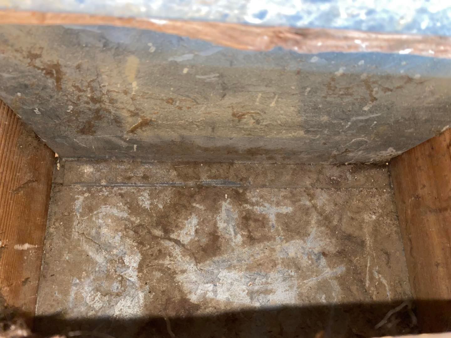 Rusty metal box interior with worn, stained surfaces and debris at the bottom