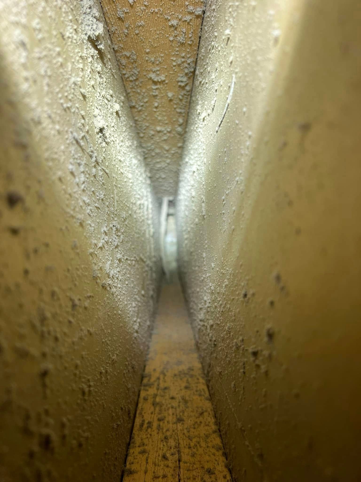 Narrow beige corridor with speckled walls and a bright opening at the far end