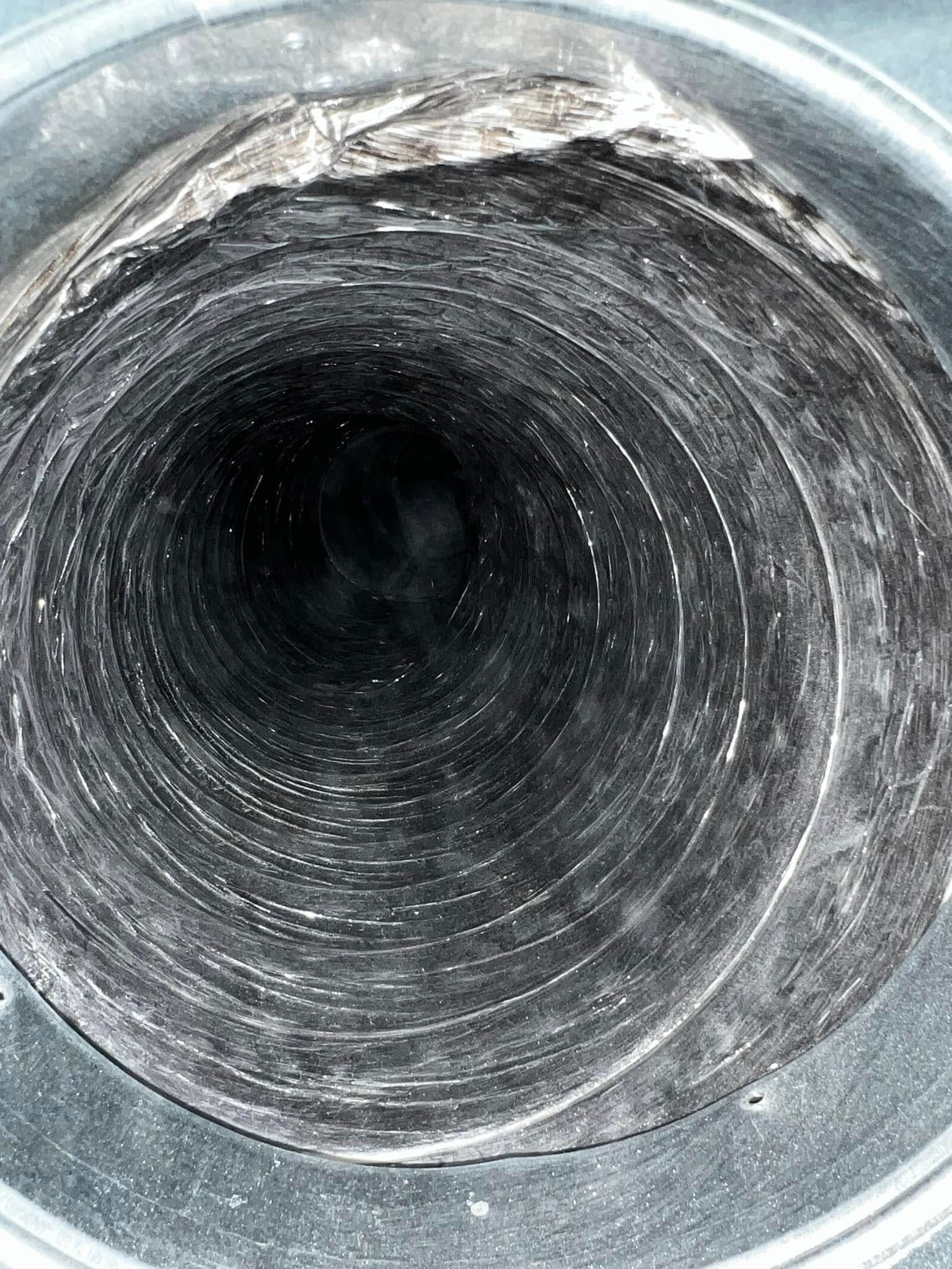 Close-up of a scratched metal pipe opening with a dark center