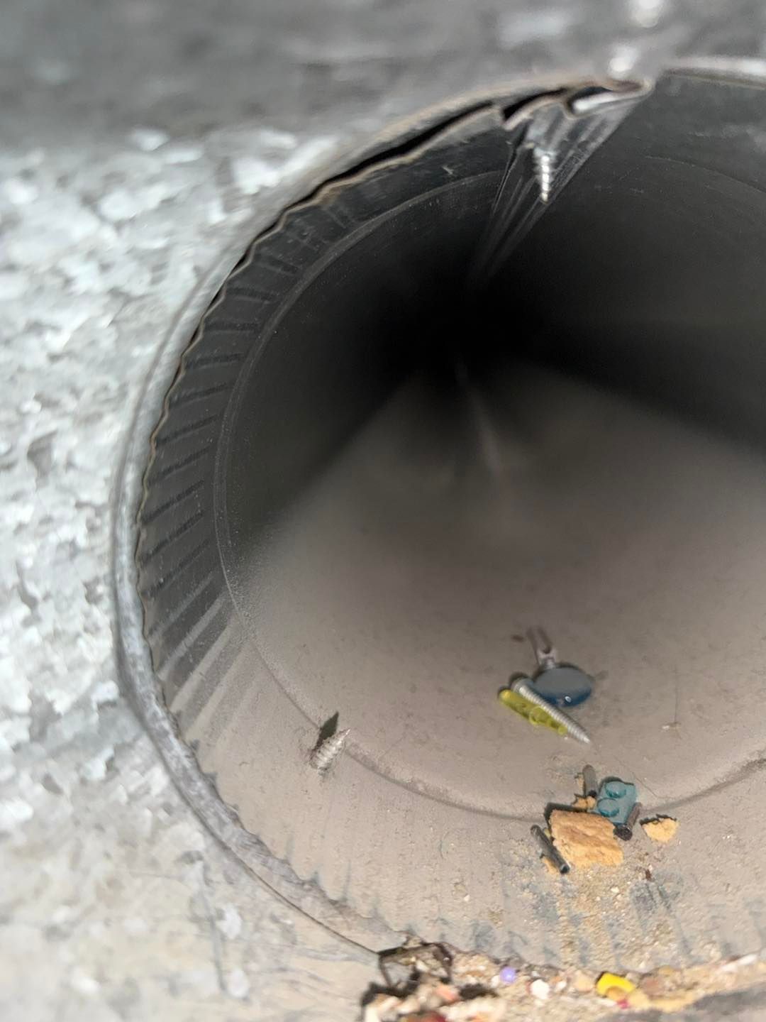 Inside a gray metal pipe with small debris and leaves on the bottom