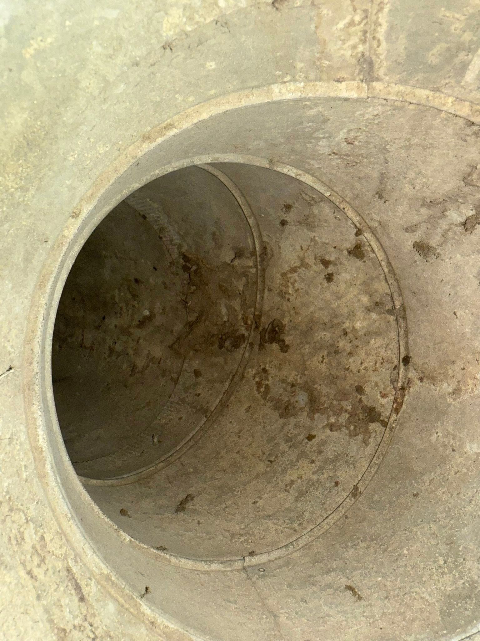 Close-up of a dirty concrete pipe opening with a circular tunnel inside