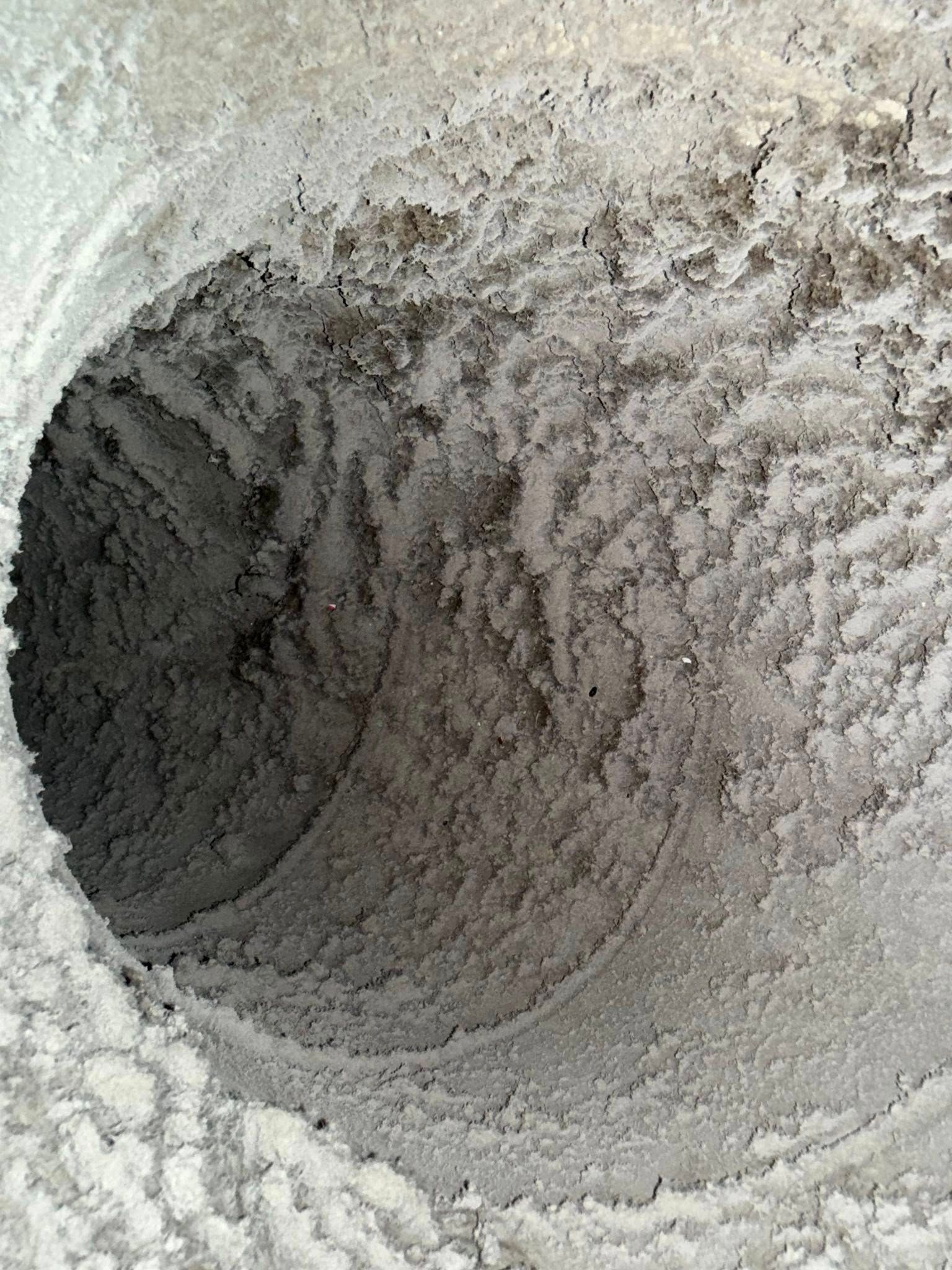 Close-up of a rough, powdery white tunnel or pipe interior with a dark opening at the left.