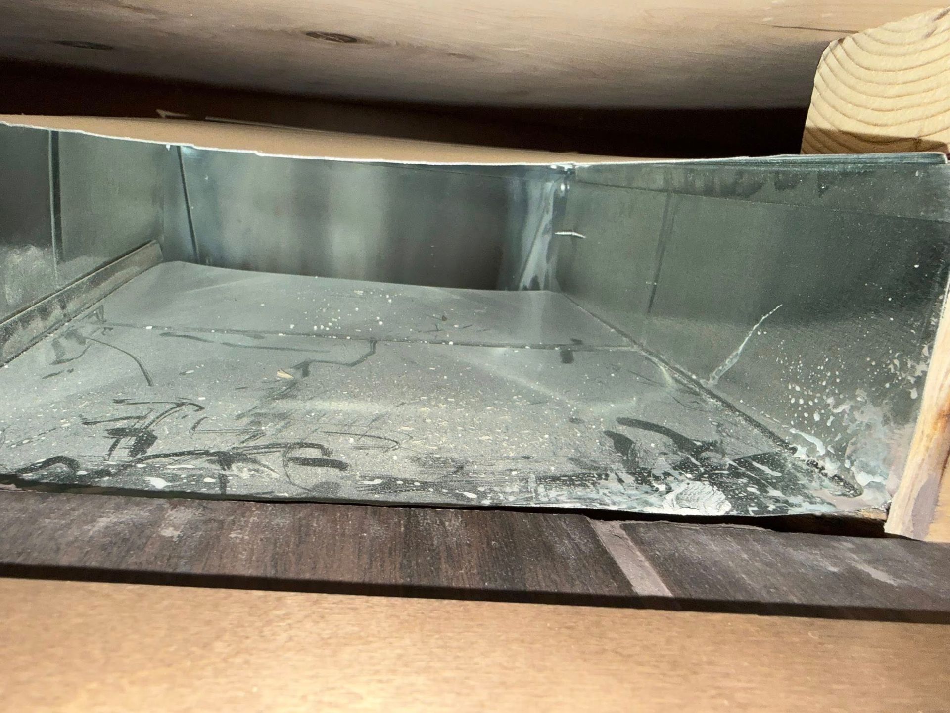 Empty metal fireplace or duct opening with soot and ash inside