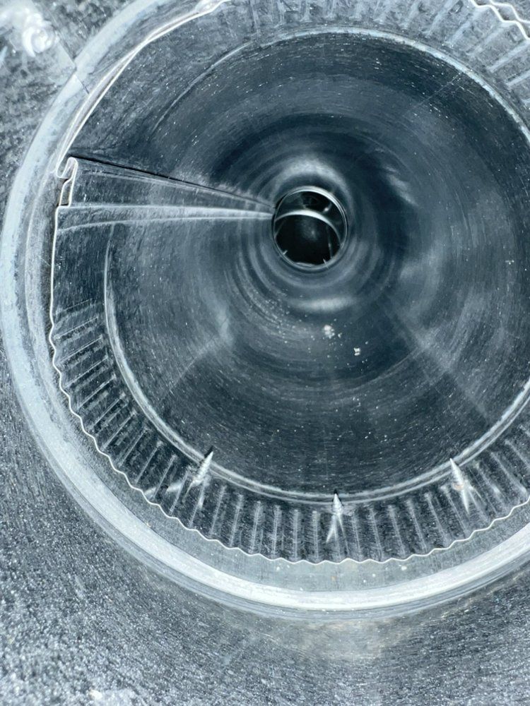 Close-up of a metallic spiral tube or vent interior with a dark central opening