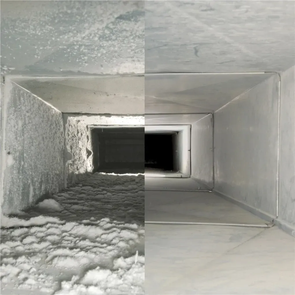 Interior of a metal ventilation duct with dust and debris buildup, ending in a dark opening