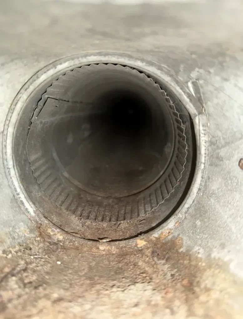 Close-up of a metal pipe opening with a dark interior and rust-stained surface