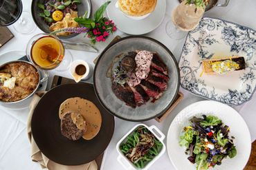 A table topped with plates of food and wine glasses. Steakhouse in Richmond, Virginia