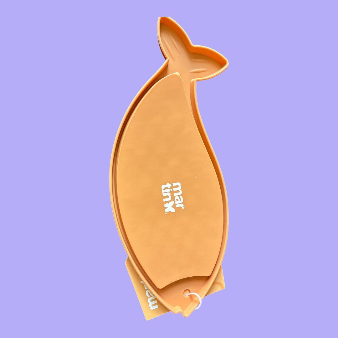 Beige, visvormige hanger met een schubbenpatroon op een lavendelkleurige achtergrond.
